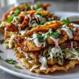 A close-up view of golden fried wonton shells filled with spicy chicken and crunchy slaw.