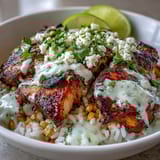 Sizzling Street Corn Chicken and Rice Bowls feature zesty crema drizzled over cotija cheese and fresh cilantro. 