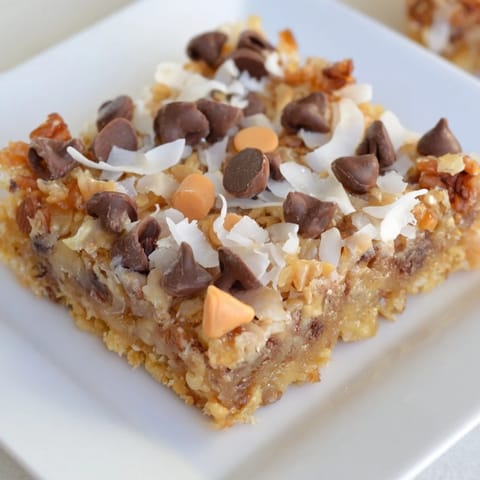 Square slices of chewy Magic Cookie Bars with layers of chocolate, coconut, and nuts, ready to eat.