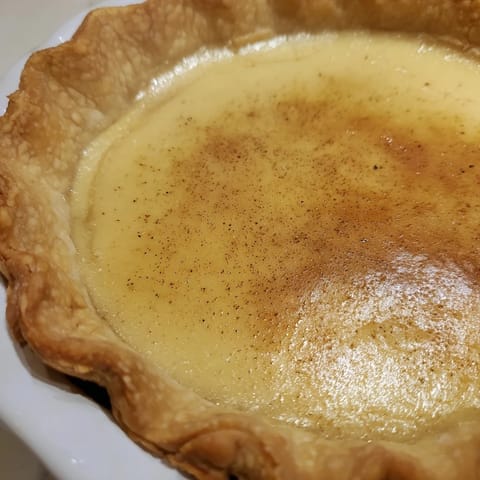 Golden-brown slice of buttermilk pie, with a creamy filling, ready to serve and enjoy.