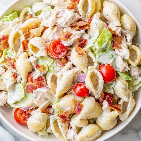 A hearty bowl of BLT Chicken Pasta Salad with cherry tomatoes and creamy dressing, perfect for a potluck.  