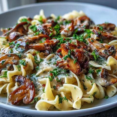 A warm skillet of Creamy Mushroom Stroganoff with rich brown sauce, paired with a glass of white wine.
