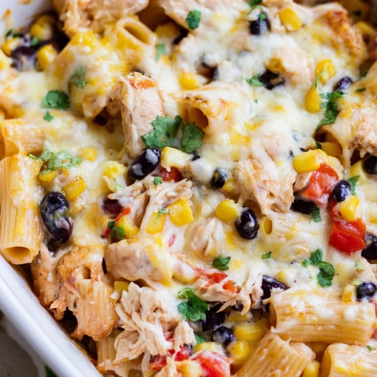 Top view of Chicken Burrito Pasta Bake garnished with fresh cilantro, jalapeños, and lime wedges on a rustic wooden table.
