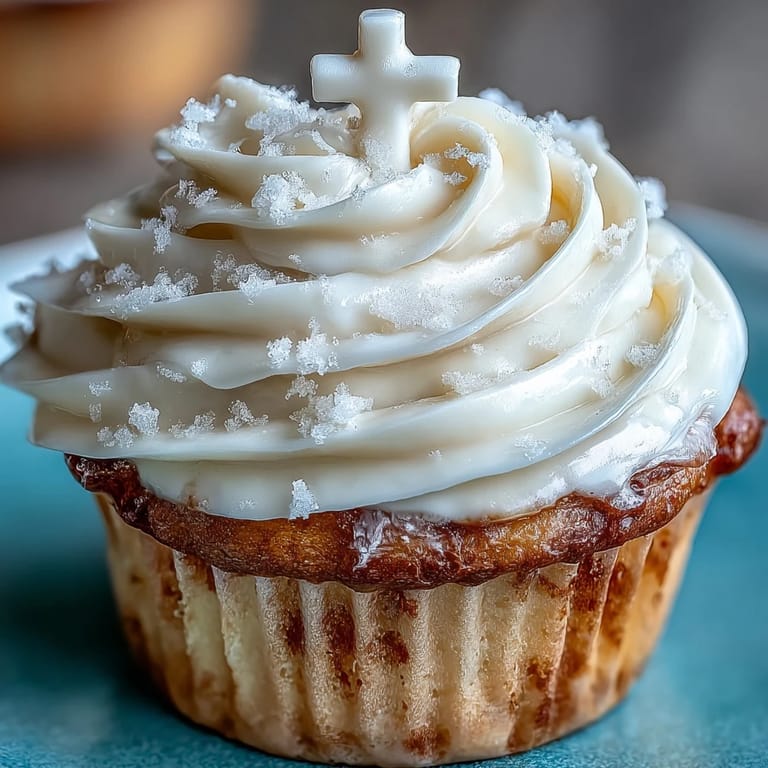 Soft vanilla cupcakes decorated with smooth buttercream frosting and delicate fondant cross toppers, ideal for sacred occasions.  