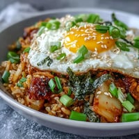 Spicy fermented cabbage kimchi fried rice bowl with a sunny-side-up egg.